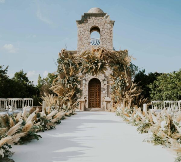 A luxury outdoor wedding, with a white carpet leading to a rustic chapel adorned with pampas grass. Your Luxury Wedding in Tangier.